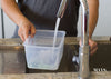 A man collecting hot water from a tap by the sink to prepare to clean a jade bangle.