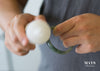 A person rubbing a jade bangle with a candle to wax it.