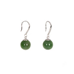 Pair of green bead earrings with silver hooks on a white background