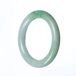 A close-up image of a round, certified natural green white jadeite bracelet. The bracelet is 58mm in diameter and is sold by MAYS GEMS.