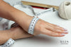 back of woman's hand with tape measure wrapped around. mays jade bangle sizing guide.