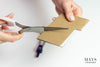 picture of a woman cutting cardboard to shape. mays jade bangle sizing guide.