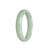 A close-up photo of a beautiful green jade bracelet with a half-moon shape, made of certified natural light green jadeite jade. The bracelet has a smooth surface and a polished finish, showcasing the natural beauty of the jade stone. Perfect for adding an elegant touch to any outfit.