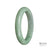 A close-up image of a green jade bracelet, showcasing its smooth texture and vibrant color. The bracelet is made from genuine Type A Green Burma Jade, and has a semi-round shape with a diameter of 58mm. The brand name "MAYS" is engraved on the inner side of the bracelet.