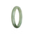 A close-up photo of a half moon-shaped light green Burmese Jade bangle bracelet, known for its authenticity and high quality.