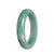 A close-up image of a green jadeite jade bangle with a half moon shape, measuring 58mm in diameter. This bangle is certified as Type A jade and is sold by MAYS GEMS.
