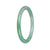 A close-up of a small, round apple green jadeite bangle with a smooth surface and a grade A quality. The bangle measures 57mm in diameter and is perfect for petite wrists.