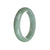 A close-up image of a pale green jade bracelet, with a smooth surface and a half-moon shape. The bracelet is made of high-quality Grade A jadeite jade and measures 59mm in diameter. It is a beautiful and elegant piece of jewelry by MAYS™.