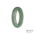 A close-up image of a half moon-shaped green jade bracelet with a smooth texture and vibrant color.