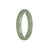 A close-up image of a half-moon shaped, genuine Type A Green Burma Jade bangle with a diameter of 57mm. The bangle has a smooth and polished surface, showcasing the beautiful green hue of the jade. It is a high-quality piece from MAYS™.