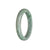 A close-up photo of a half-moon shaped bangle made of untreated grey with green Burma jade. The bangle is certified and measures 57mm in diameter. The jade has a smooth and polished surface, showcasing its natural beauty.