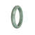 A half moon-shaped jade bangle with a natural untreated green and grey color.