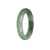 A close-up image of a half-moon shaped green and pale green jadeite jade bangle bracelet. The bracelet is made of high-quality grade A jade, showcasing its vibrant color and smooth texture. The intricate details and natural variations of the jade are visible, making it a beautiful and unique accessory.
