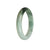 A close-up image of a white and green jade bangle bracelet, featuring a half-moon shape and measuring 57mm in diameter. The bangle is made of genuine Type A jade and is sold by MAYS GEMS.
