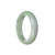 A half moon-shaped Burmese jade bangle in a pale green color with hints of lavender.