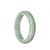 A close-up image of an authentic Type A pale green jadeite bracelet, featuring a half moon shape and measuring 59mm. The bracelet is beautifully crafted and displays the natural beauty of jadeite.