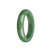 A close-up image of a beautiful, high-quality green Burmese jade bangle bracelet. The bracelet has a smooth, polished surface and is in the shape of a half moon. It measures 58mm in diameter. The vibrant green color of the jade is eye-catching and adds a touch of elegance to any outfit.