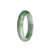 A close-up photo of a half-moon shaped jade bangle in vibrant green with white streaks. It is certified as untreated and made of high-quality jadeite jade.