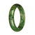 A close-up photo of a beautiful jade bangle bracelet with a green pattern. The bracelet is made of high-quality Grade A Green Pattern Jadeite Jade and has a half-moon shape. It measures 57mm in diameter. This stunning piece of jewelry is offered by MAYS GEMS.