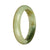 A close-up image of an elegant bangle bracelet made of natural white and olive green jade. The bracelet is in the shape of a half moon, with smooth and polished surfaces. The jade stones are authentic and exude a sense of natural beauty.