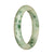 A close-up of a beautiful jade bangle bracelet with a half moon pattern in shades of white and green.