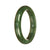 A close-up image of a half-moon-shaped green jade bangle bracelet, showcasing its smooth texture and vibrant color.