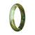 A close-up image of a beautiful green and white jade bangle with a traditional pattern, featuring a half-moon shape. This genuine Grade A jade bangle is 59mm in size and is sold by MAYS.