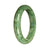 A close-up photo of a stunning jade bangle bracelet in shades of green and light green. The bracelet features a unique pattern and is made of genuine Type A Burmese jade. It has a 55mm diameter and a half-moon shape. A luxurious piece of jewelry from MAYS GEMS.