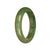 A close-up image of an authentic natural green jadeite jade bracelet with a 51mm half moon shape. The jadeite jade bracelet shines in various shades of green, showcasing its natural beauty. It is a stylish accessory that adds elegance to any outfit.