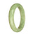 A close-up photo of a half moon-shaped bracelet made of certified natural light green jadeite. The bracelet is 58mm in size and is offered by MAYS GEMS.