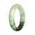 A close-up image of a pale green jade bangle bracelet with a green pattern, in a half moon shape. The bracelet has a smooth and polished surface, showcasing the natural beauty of the jade.
