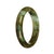 A close-up image of a beautiful half moon shaped jade bracelet with a green pattern.