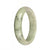 A pale green and white jade bangle with dark green patterns, in a half moon shape, measuring 59mm.