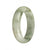 A close-up image of a jadeite jade bangle bracelet. The bracelet is made of certified Grade A white jade with an olive green pattern. It is in the shape of a half moon and has a diameter of 55mm. This item is sold by MAYS GEMS.
