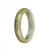 A beautiful and authentic half moon-shaped jade bangle bracelet in pale green and brown colors.