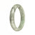 A half moon-shaped Burmese jade bangle with beautiful green color and intricate grey patterns.