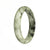 A close-up image of a jadeite bangle bracelet with a half moon shape. The bracelet is white with dark green patterns.