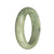 A half moon-shaped, genuine Burmese jade bangle bracelet in light green and light grey colors with deep green spots.