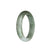 A beautiful half moon-shaped Burmese jade bangle with a mix of white and green colors, adorned with brown spots.