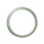 A close-up image of a delicate half-moon-shaped bangle bracelet made of genuine untreated pale green jadeite. The bracelet measures 57mm in diameter and features a smooth and polished surface. The jadeite stone has a soft and soothing green hue, giving the bracelet a tranquil and elegant appearance. Created by MAYS™.