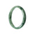 A close-up image of a half-moon shaped green Burmese jade bangle bracelet, certified as Grade A quality. The bracelet has a smooth, polished surface and measures 59mm in diameter. The jade is a vibrant shade of green, representing natural beauty and elegance. This bangle bracelet is part of the MAYS™ collection, known for its exceptional craftsmanship and luxury.