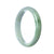 A close-up image of a pale green traditional jade bangle with a smooth, half-moon shape. The bangle appears to be made of authentic, natural jade and is approximately 57mm in size. This piece of jewelry is sold by MAYS GEMS.